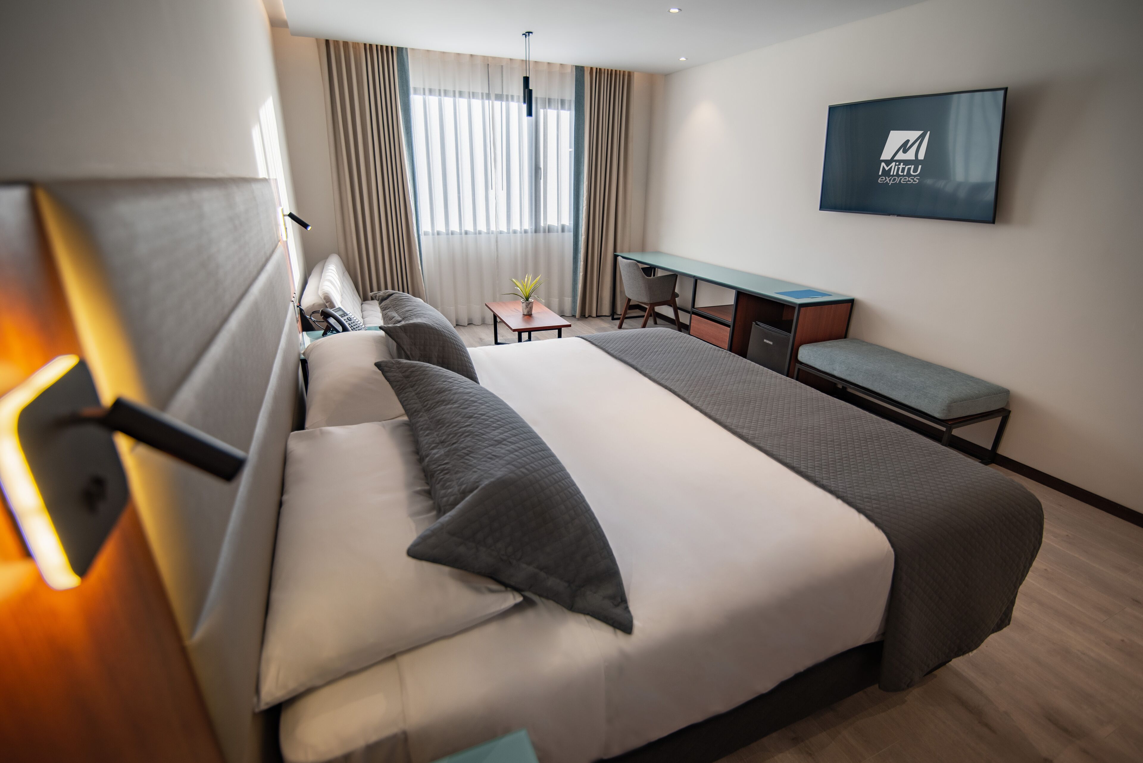 Una habitación de hotel moderna con una cama grande, un escritorio y un televisor.