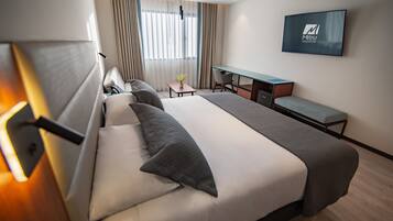 Una habitación de hotel moderna con una cama grande, un escritorio y un televisor.