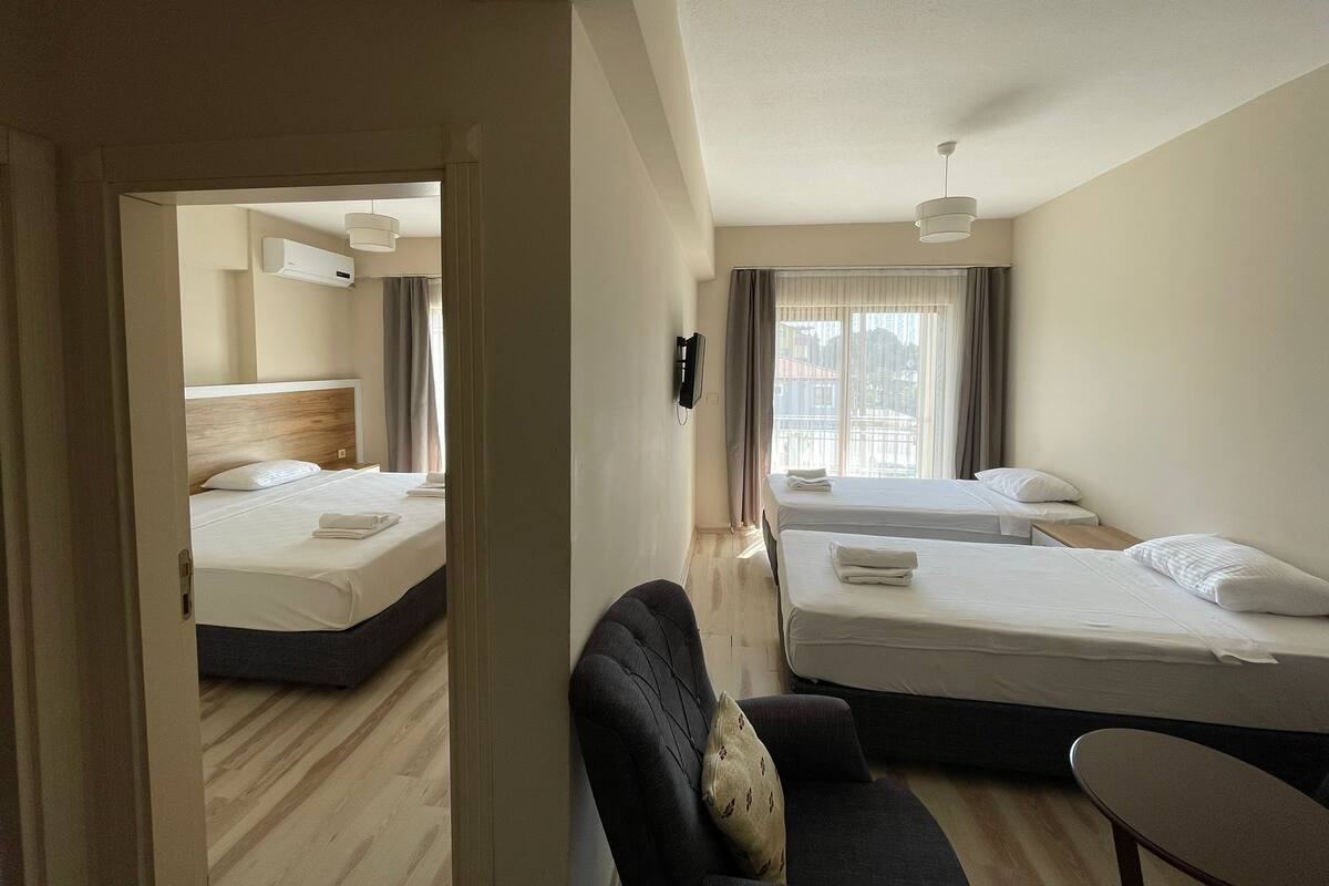 A hotel room with two beds, a sofa, a small table, and a view of the city.