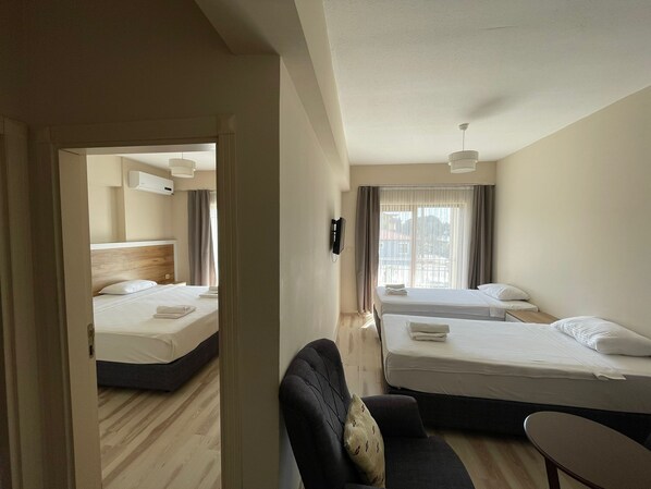 A hotel room with two beds, a sofa, a small table, and a view of the city.