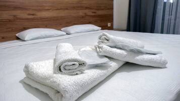 Una cama bien hecha con sábanas blancas y cabecera de madera.