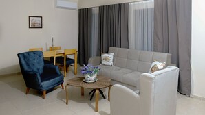 A living room with a sofa, armchair, and a small table with a flower vase.