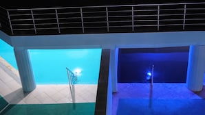 An indoor swimming pool with tiled floors and a green mat at the bottom of the stairs.