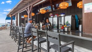 Zona de bar al aire libre con asientos y barra.