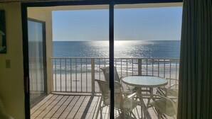 Un balcón con puerta de cristal que da a una vista de la playa.