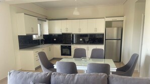 Una cocina moderna con armarios blancos, encimera negra y refrigerador de acero inoxidable.