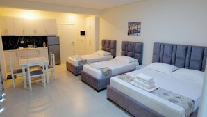 Habitación de hotel con dos camas, una kitchenette pequeña y un comedor.