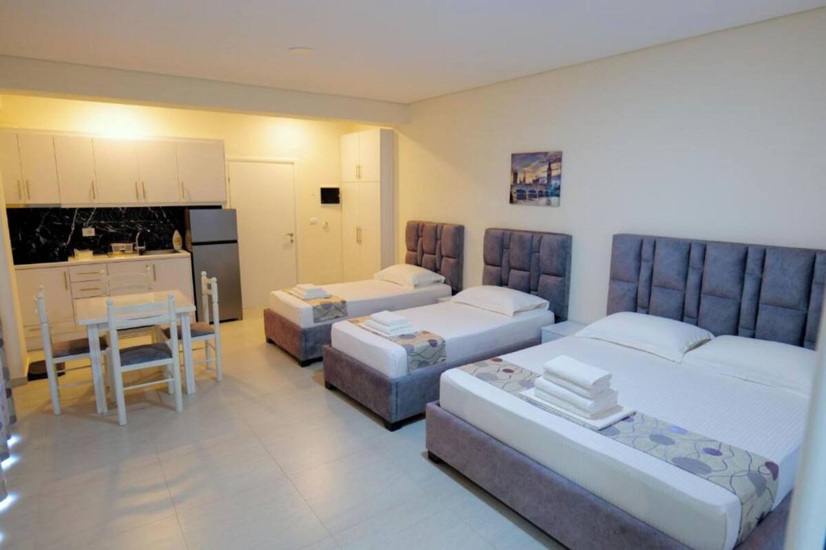 Habitación de hotel con dos camas, una kitchenette pequeña y un comedor.