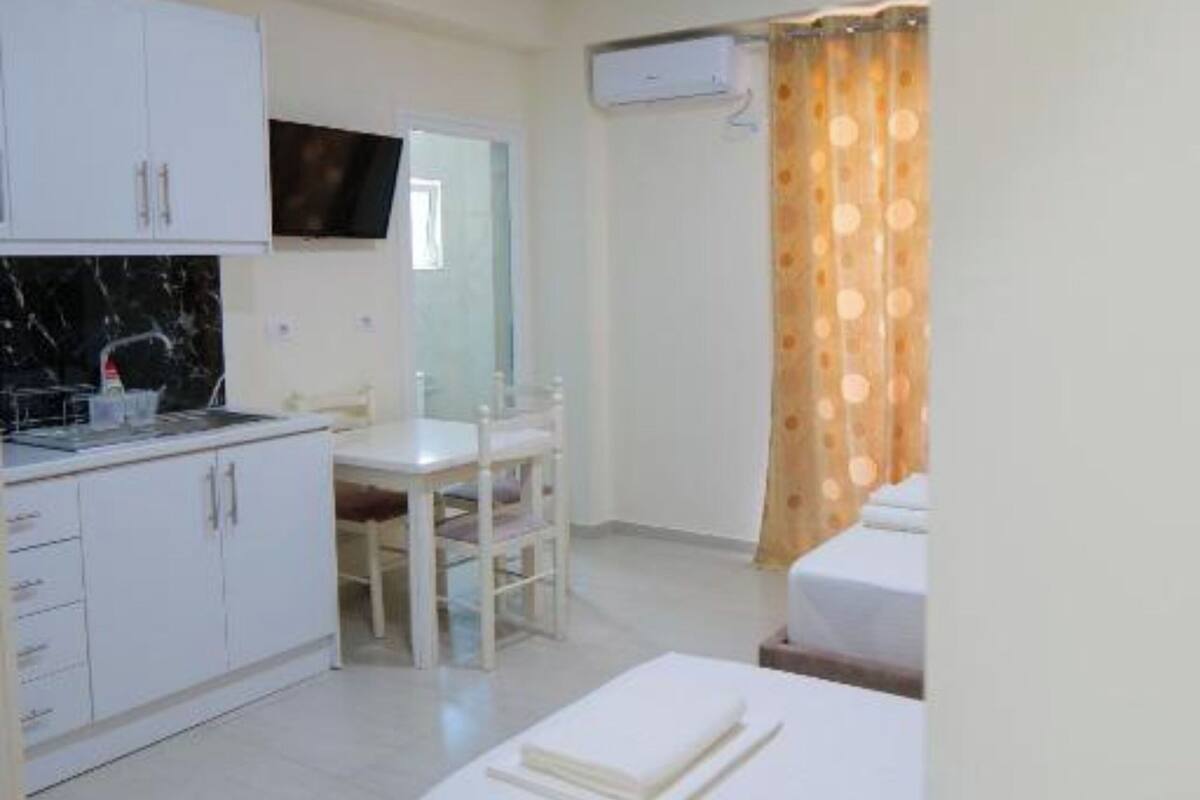 Una habitación de hotel compacta con cama, kitchenette pequeña, zona de comedor y baño.