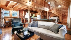 A cozy cabin interior with a wooden interior, a sofa, a chair, a dining table, and a pool table. - Sweet Dreams - Romantic and Hot Tub (Sevierville)