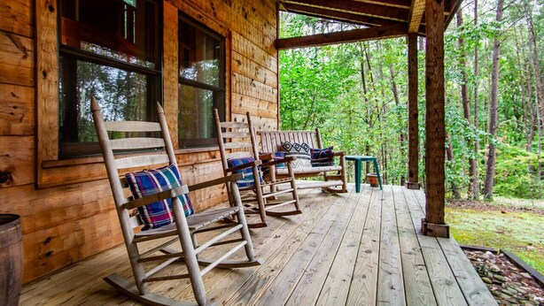 A wooden cabin with a porch, rocking chairs, and a view of the forest. - Sweet Dreams - Romantic and Hot Tub (Sevierville)
