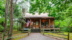 A rustic cabin with a porch, an American flag, and a sign reading "T Sweet Dreams." - Sweet Dreams - Romantic and Hot Tub (Sevierville)