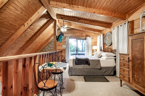 Un dormitorio de cabaña de madera con cama, cómoda y zona de comedor con sillas.