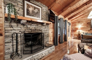 A stone fireplace with a metal screen, a wooden mantel, and a framed picture above it. - Peekaboo - Hot Tub, Pool Table, and Jacuzzi! (Sevierville)