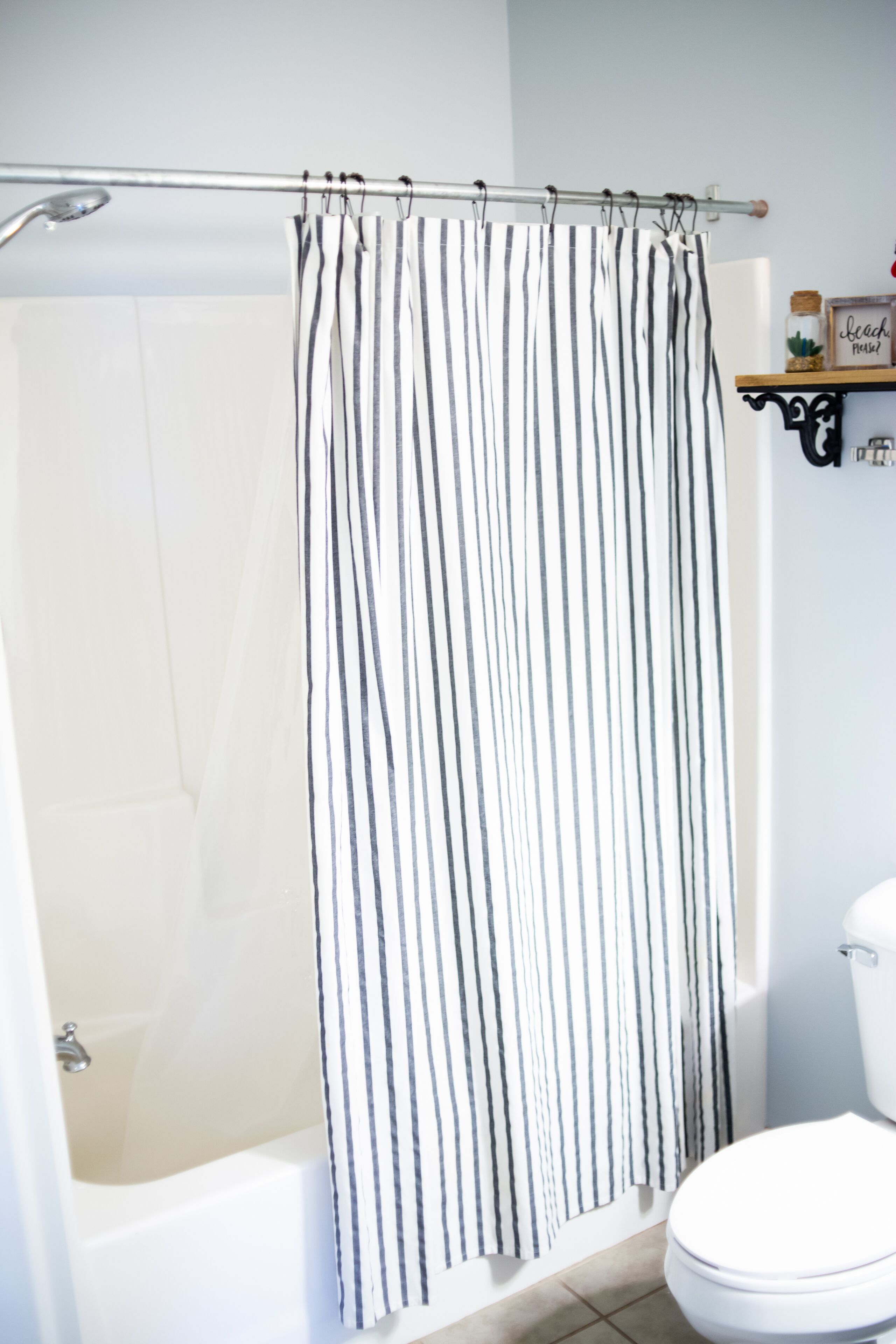 A bathroom with a white bathtub, a white toilet, and a striped shower curtain.