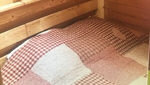A wooden cabin room with a single bed, a wooden headboard, and a wall-mounted light fixture. - 2P FRONT DE NEIGE SUD CALME (Isola)