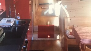 A compact kitchen with a sink, a red cabinet, and a small dining area with a checkered tablecloth. - 2P FRONT DE NEIGE SUD CALME (Isola)