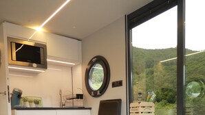 Eine moderne Küche mit weißen Schränken, einer Mikrowelle und einem Fenster mit Blick auf eine grüne Landschaft.