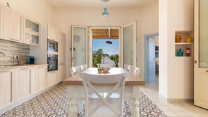 A kitchen with a dining table, chairs, and a view through an open door.