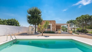 A swimming pool with a stone structure and trees in the background.