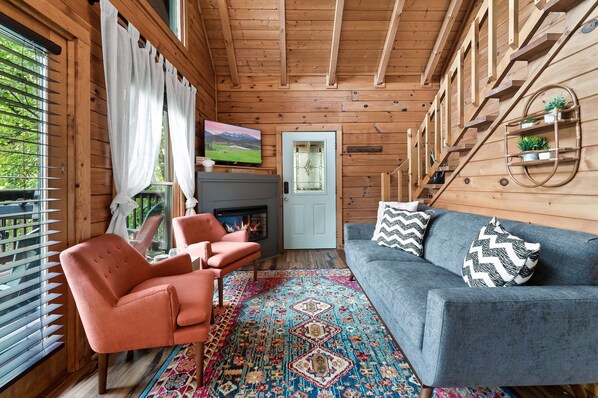 L'intérieur d'un chalet en bois chaleureux et accueillant, avec une cheminée, un canapé et un téléviseur.