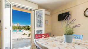 A room with a table set for dining, a potted plant, and a view of a pool and palm trees outside. - Villa Tina Maria by Perle di Puglia (San Pietro in Bevagna)