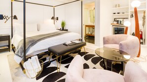 Una habitación de hotel moderna con una cama con dosel, una mesita, una silla y una mesa redonda de cristal.
