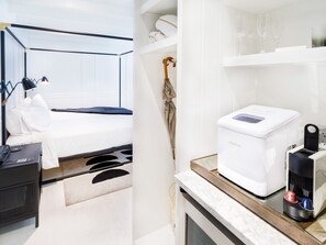 A modern hotel room with a bed, bedside table, and a minibar. - American Beech in Greenport - King Suite 3 (Greenport)