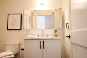 A bathroom with a white sink, a mirror, and a toilet. - American Beech in Greenport - King Suite 3 (Greenport)