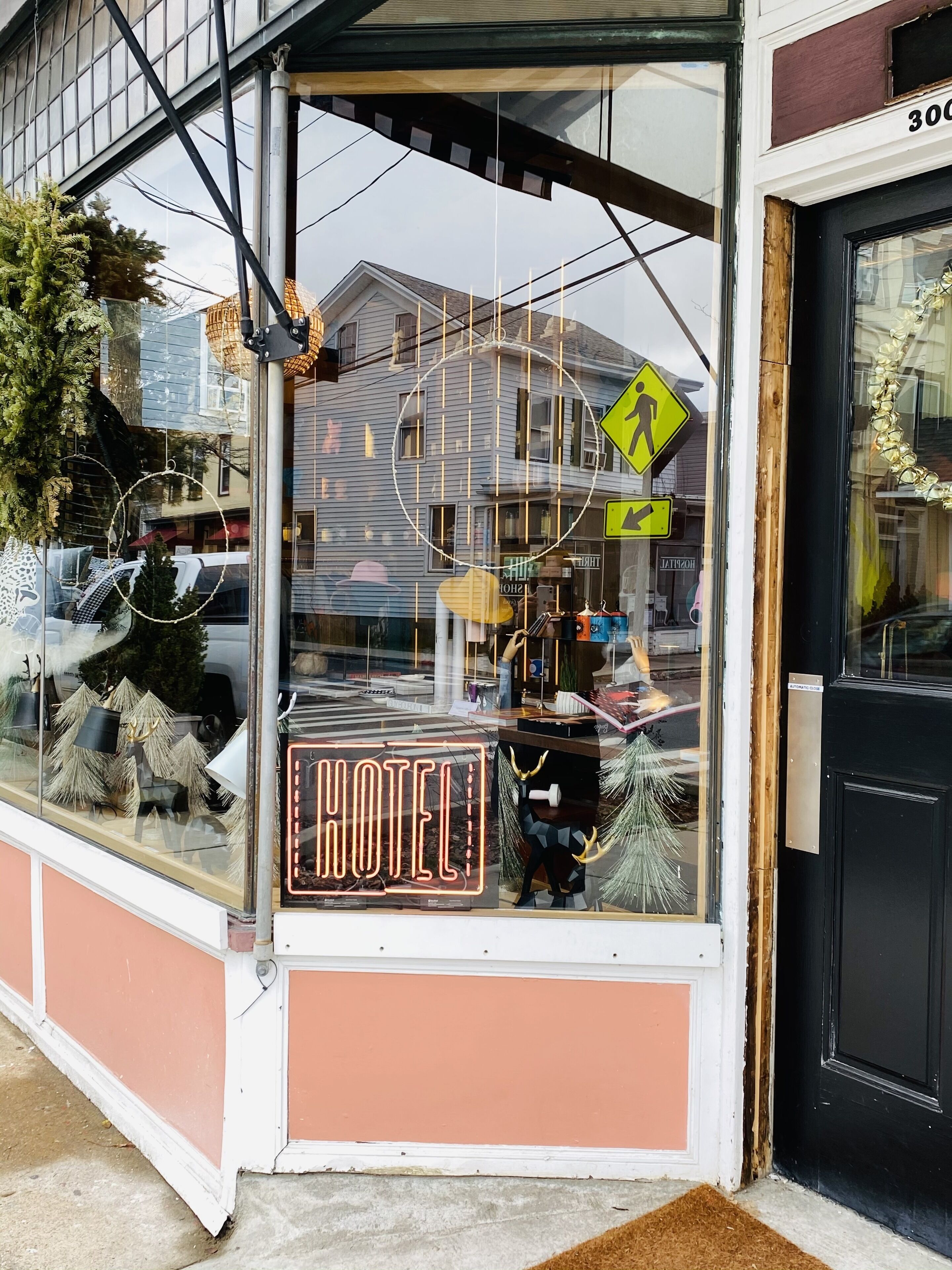 Un hotel con un letrero de neón, una señal de paso de peatones y el reflejo de un edificio en el ventanal.