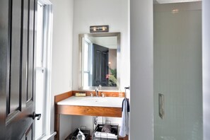 Un baño con tocador de madera, un espejo y cabina de ducha.