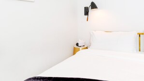 A hotel room with a bed, a bedside table with a lamp, a wall-mounted clock, and a framed abstract artwork. - American Beech in Greenport - Two-Bedroom Apartment 8 (Greenport)