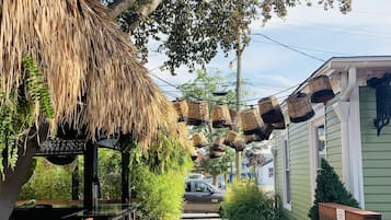 A pathway leading to a building with a thatched roof and hanging baskets.