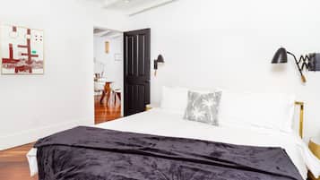 Een slaapkamer met een groot bed, een zwarte deur, een witte muur en een kunstwerk in een lijst.
