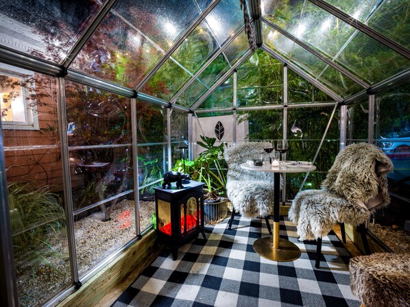 A greenhouse with a checkered floor, a table with a lamp, and a potted plant.