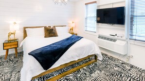 Un dormitorio moderno con cama, mesitas de noche, televisor y lámpara en el techo.