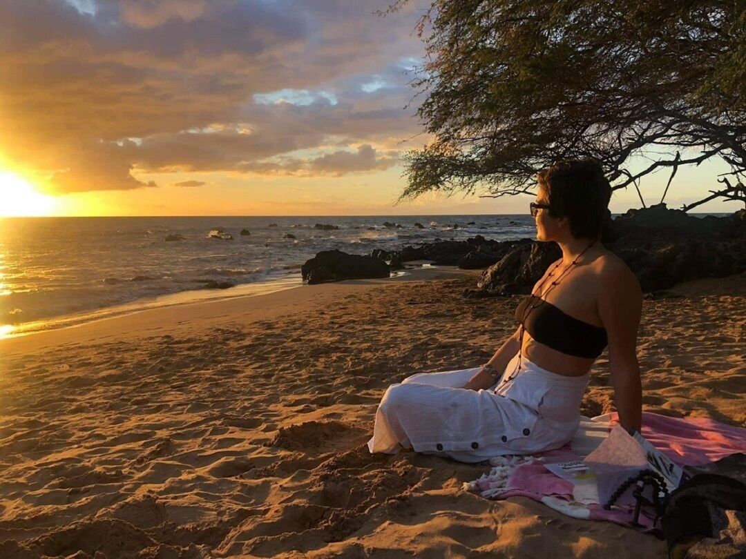 A person sitting on a beach at sunset.