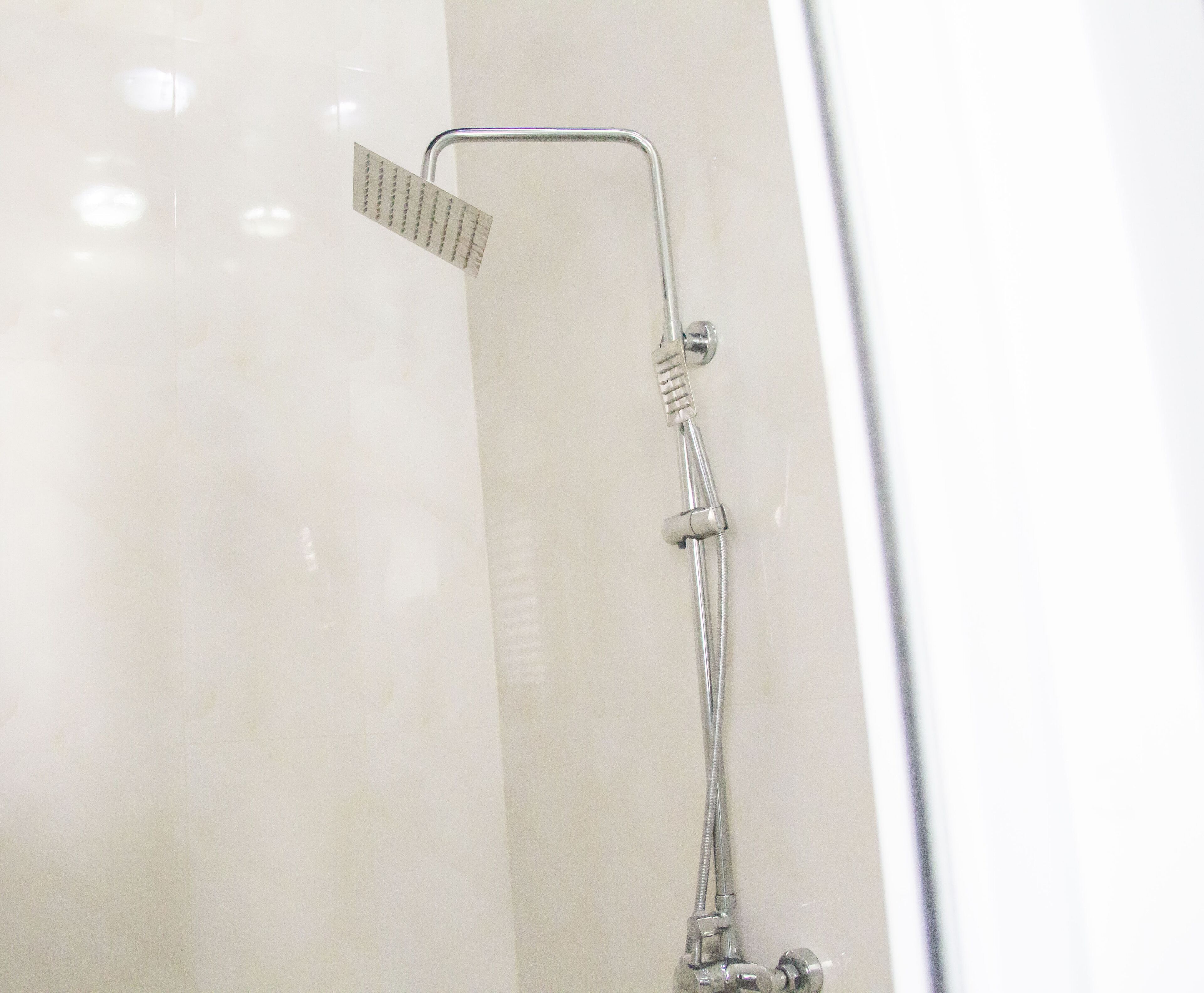 A shower with a handheld showerhead and a handheld scrubber.