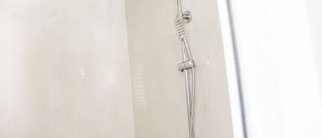 A shower with a handheld showerhead and a handheld scrubber.