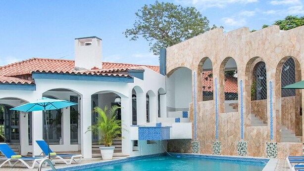 A swimming pool with blue tiles, lounge chairs, and a tiled deck. - High Life Villa (Negril)