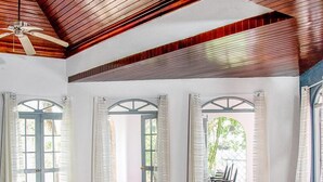 A spacious room with a large bed, a ceiling fan, and a view of the outdoors through multiple doors and windows. - High Life Villa (Negril)