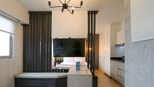 Een moderne hotelkamer met een bed, een televisie, een eethoekje en een keuken.