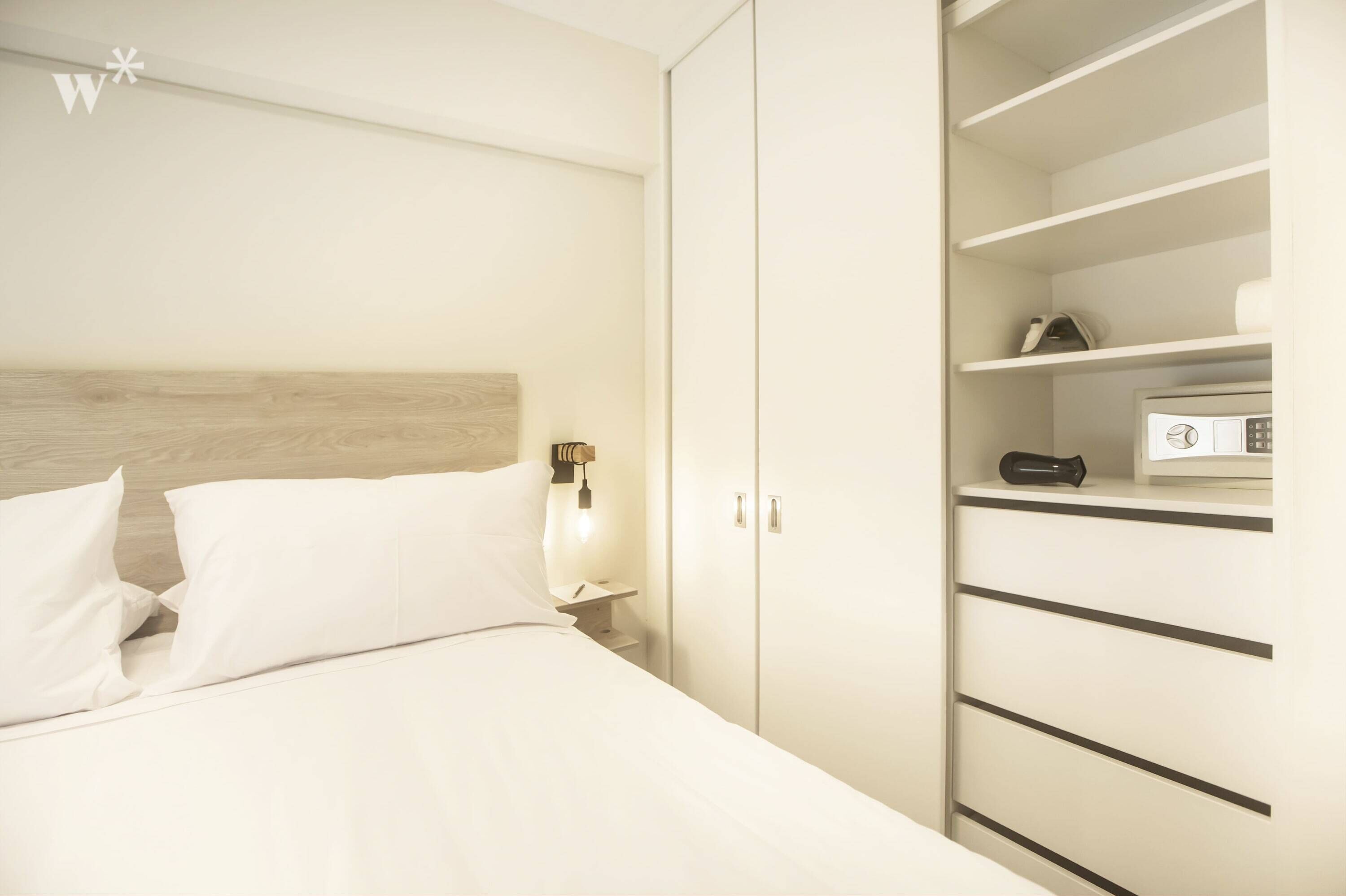 Una camera da letto con un letto, un comodino, un armadio e uno scaffale con articoli da toilette.