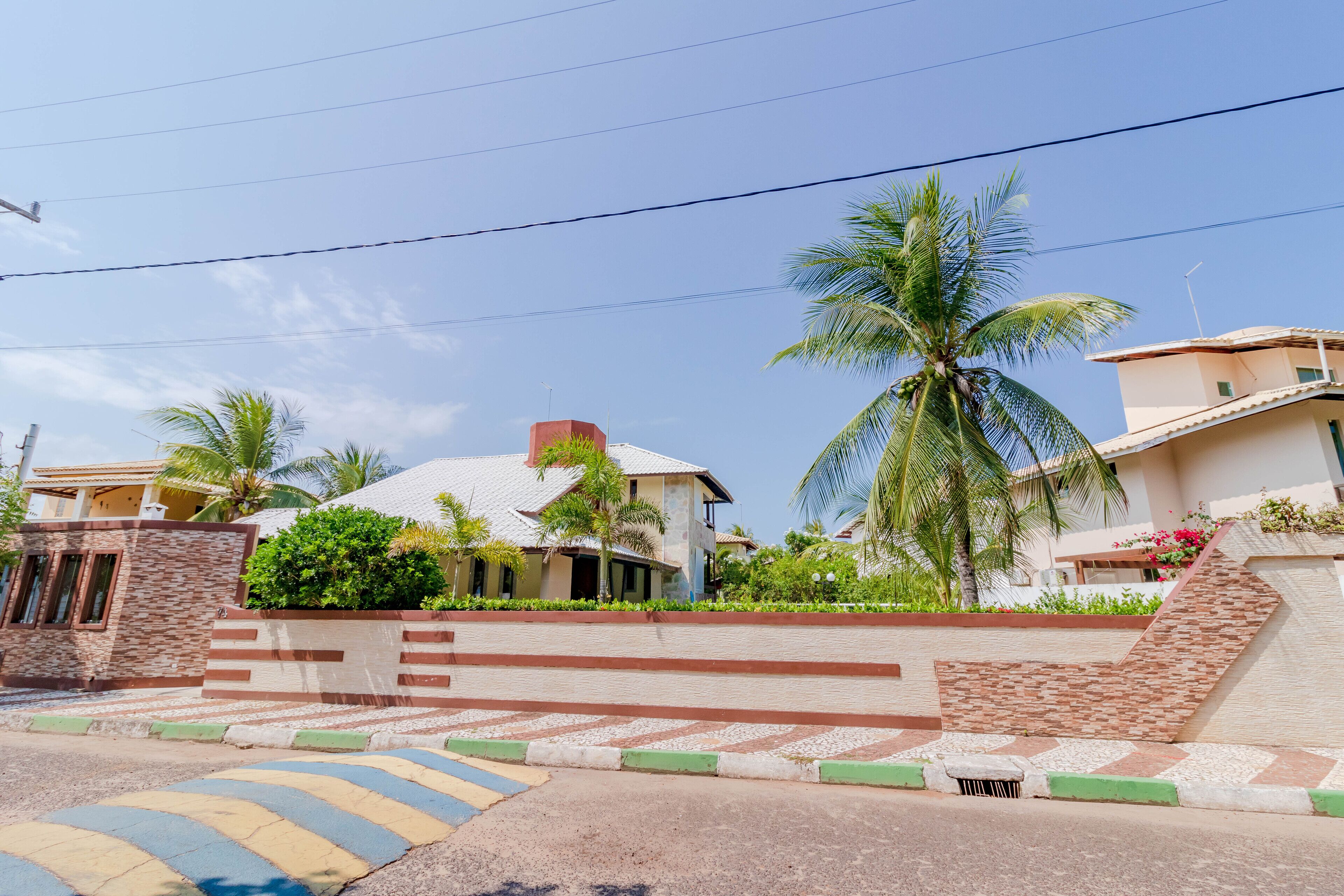 A residential area with houses, palm trees, and a clear sky.