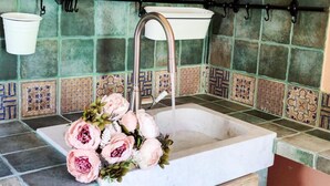 Ein Küchenspüle mit Wasserhahn, eine Blumenkomposition und eine geflieste Spritzwand.