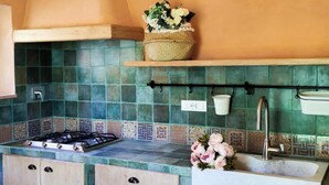 Eine Küche mit Gasherd, Holzschränken, einer Spüle und einer Rückwand mit Mosaikfliesen.
