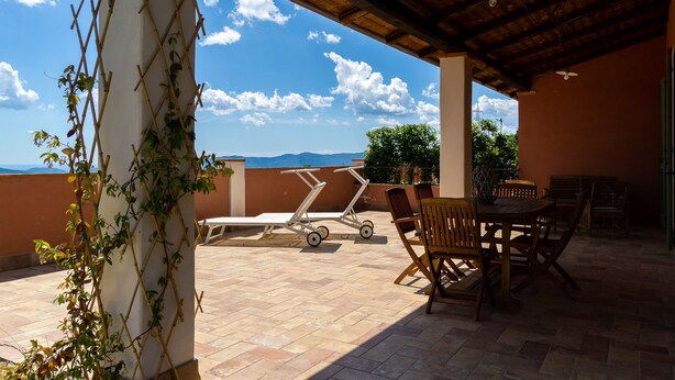 Un patio al aire libre con una mesa, sillas y un carrito.