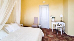 Un dormitorio con cama, una silla, un escritorio, una lámpara y una puerta.