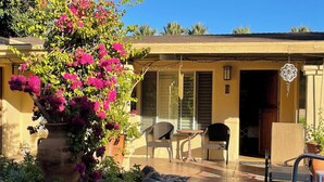 A patio area with a table and chairs, a large potted plant with pink flowers, and a small garden with rocks and plants. - 🌸Room 2️⃣ in a former boutique hotel, two blocks from Downtown Palm Springs 🌞 (Palm Springs)