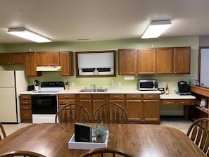 Une cuisine avec des meubles de rangement en bois, une cuisinière, un évier et une table à manger avec des chaises.
